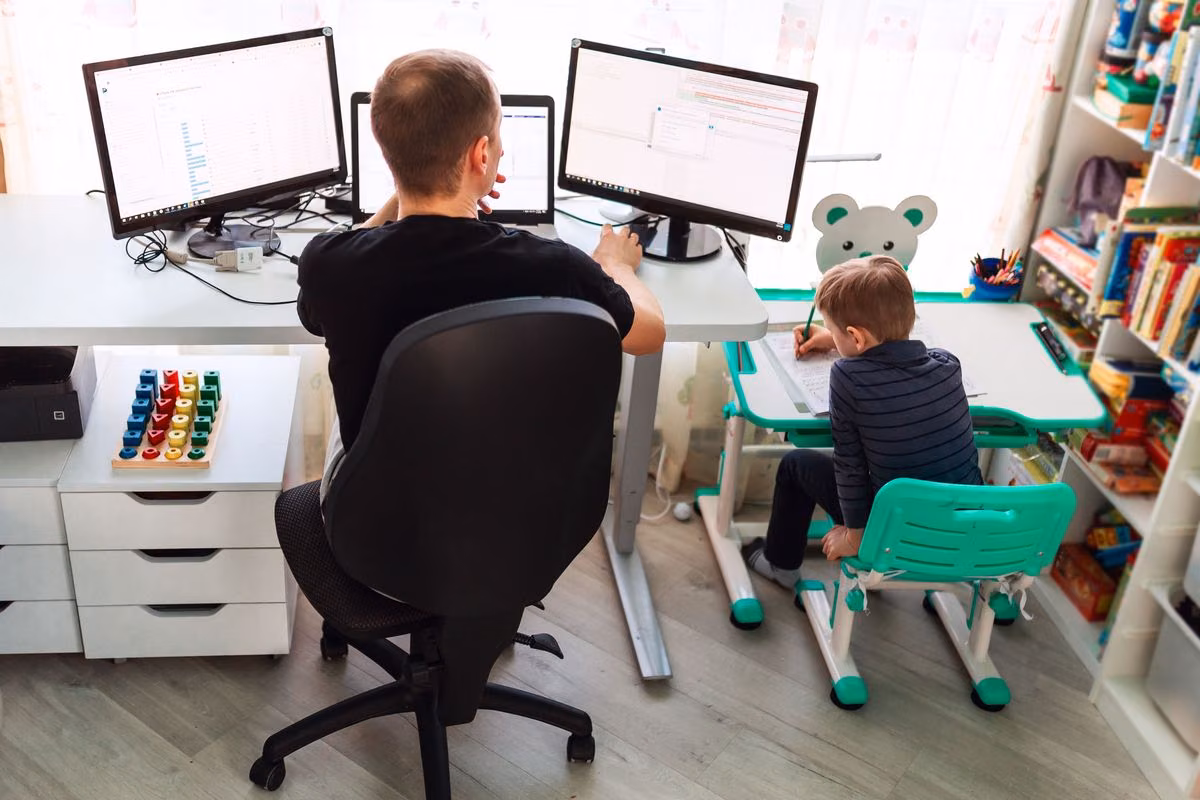 Arbeitender Vater mit Kind am Tisch